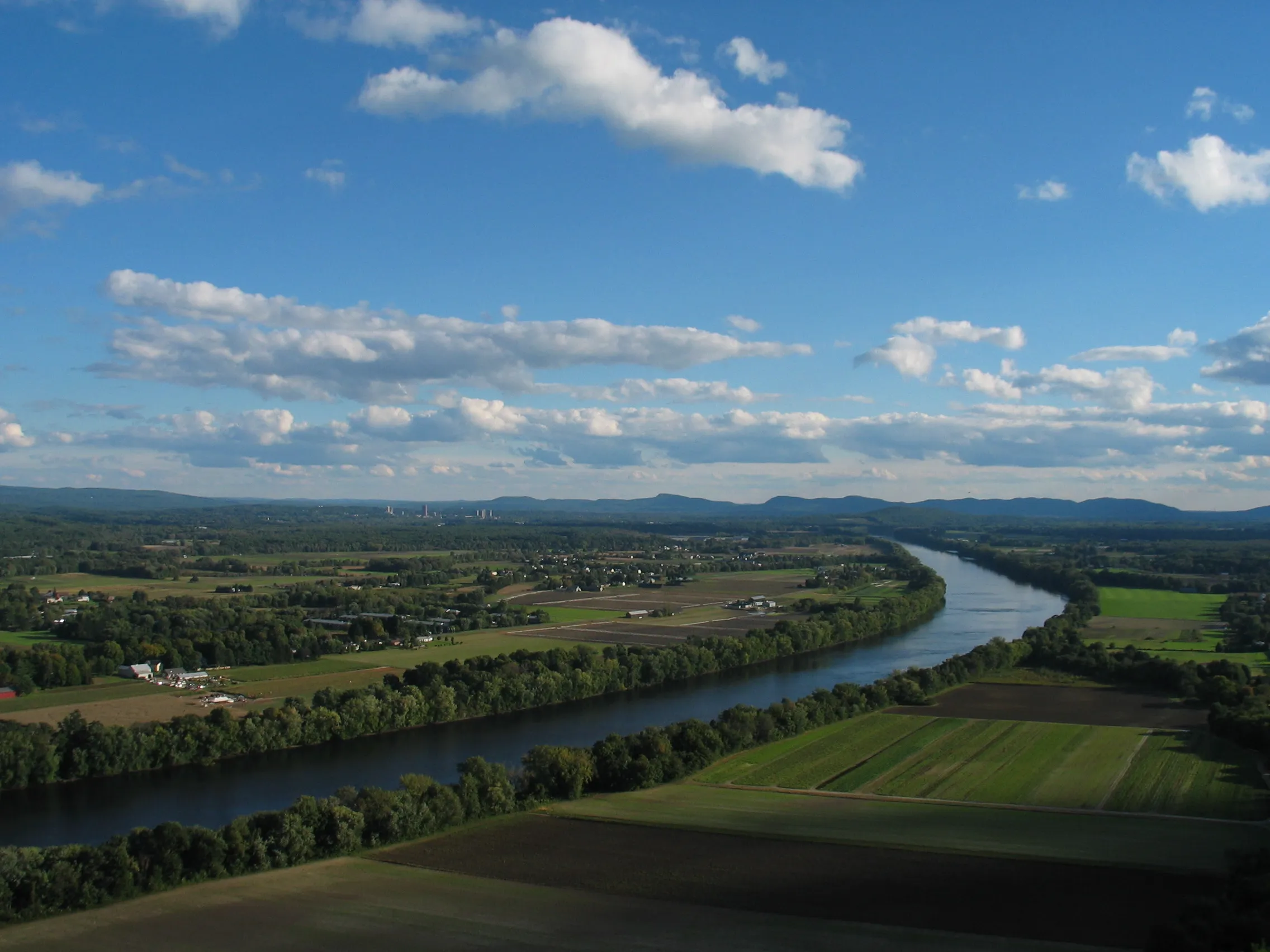 The Connecticut River Valley seen from the summit of Mount Sugarloaf: broad farm fields and the river winding south past the Holyoke Range.